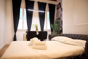 A hotel room with a bed, two chairs, a desk, a potted plant, and a window with curtains. - Modern and Comfortable Apartment - Florence City Center (Florence)