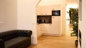 Un espacio habitable pequeño con sofá, kitchenette y una planta.