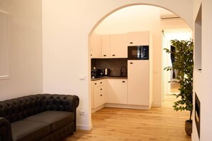 A compact living space with a sofa, kitchenette, and a plant. - Modern and Comfortable Apartment - Florence City Center (Florence)