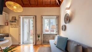 Un soggiorno moderno con un divano, un tavolo da pranzo e una zona cucina visibile attraverso una porta aperta.