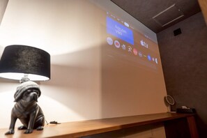 En projektionsduk som visar olika streamingtjänster, en lampa och en liten statyett på en träyta.