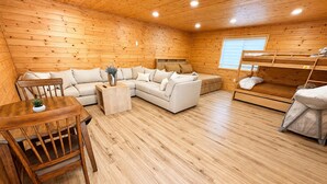 A cozy cabin interior with a wooden floor, a sofa set, a dining table with chairs, and a bunk bed. - Rock House/Riverfront/EV Charging/Large Groups (Kernville)
