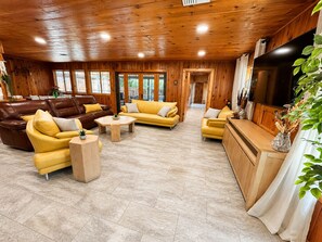 A spacious living area with wooden walls and ceiling, furnished with sofas and a coffee table.