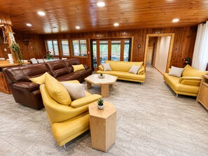 Un salon spacieux avec des canapés en cuir, une table basse en bois et une vue sur l’extérieur grâce à de grandes fenêtres.