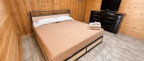 A wooden-paneled room with a bed, a dresser, and a television.