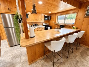 A kitchen with wooden cabinets, a stainless steel refrigerator, a microwave, and a large island with bar stools.