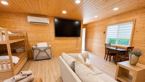 A cozy cabin interior with a sofa, bunk beds, a TV, and a dining area. - Rock House/Riverfront/EV Charging/Large Groups (Kernville)