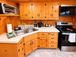 A kitchen with wooden cabinets, stainless steel appliances, and a countertop with various items.