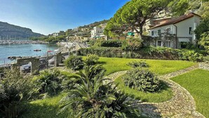 Uma vila costeira com um porto de iates, vegetação exuberante e edifícios na encosta.