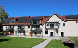 Um edifício de vários andares com telhado de telhas vermelhas, varandas e painéis solares.