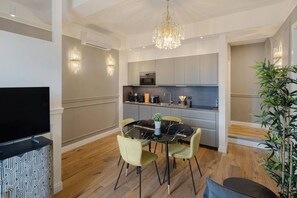 A modern kitchen with grey cabinets, a black marble dining table, and a chandelier. - Elegant and Bright Apartment Laura I (Florence)