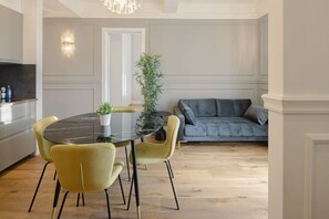 A modern dining area with a round table, yellow chairs, a potted plant, and a grey sofa in the background. - Elegant and Bright Apartment Laura I (Florence)