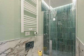 A bathroom with a glass shower enclosure, marble flooring, and a towel rack. - Elegant and Bright Apartment Laura I (Florence)