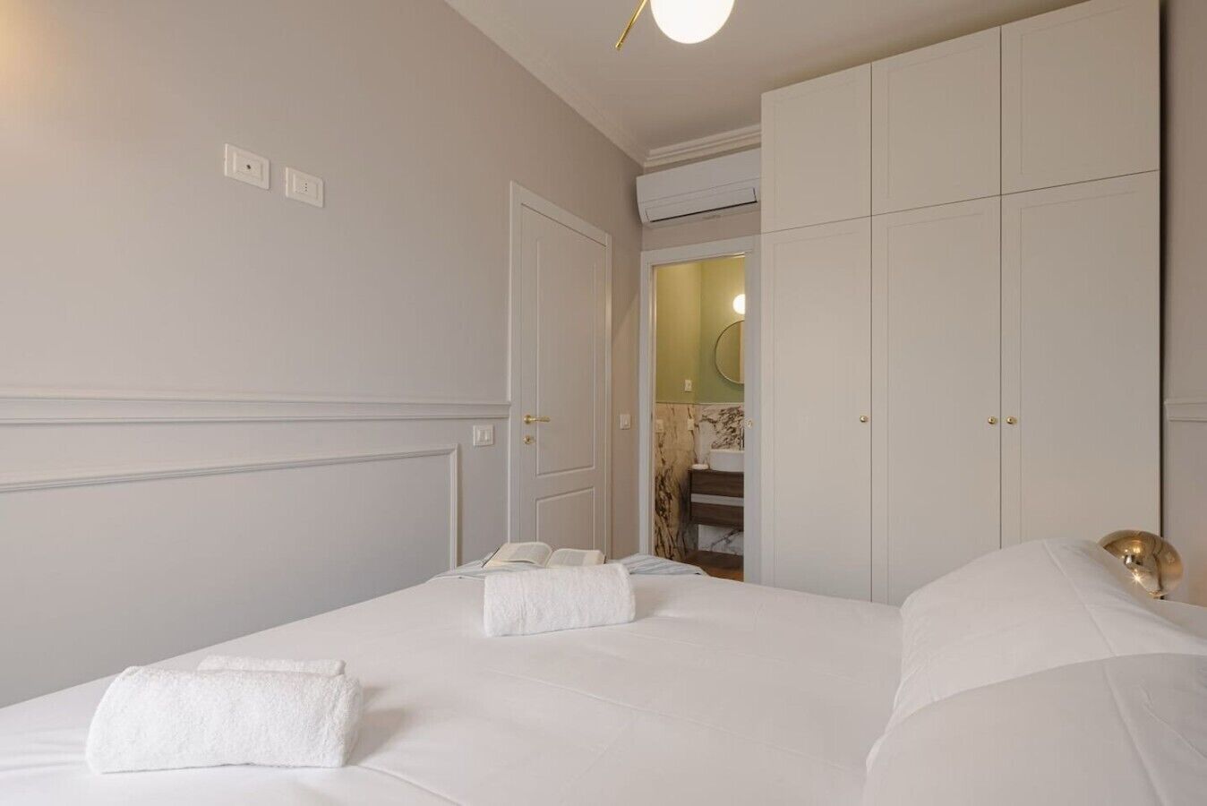 Une chambre d’hôtel avec un lit, une armoire et une salle de bain visibles à travers une porte ouverte.