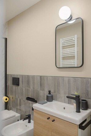 Ein Badezimmer mit einem weißen Waschbecken, einem Spiegel, einem Handtuchhalter und einer Toilette.