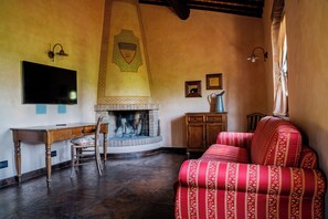 Una habitació amb una llar de foc, televisió, escriptori i un sofà vermell.