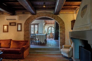 Un intérieur agrémenté d’une arche en pierre menant à un espace repas, d’une cheminée et d’un canapé en cuir.
