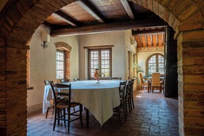 Un coin repas avec une table ronde, des chaises et un coq décoratif en guise de centre de table.