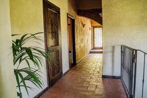 A hallway with a tiled floor, a wooden door, and a potted plant. - Authentic Tuscan Farmhouse with a Private Pool, Garden, and 7 Bedrooms (Cantagrillo)
