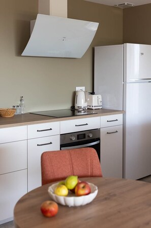 Eine kleine Küche mit einem weißen Kühlschrank, einem Herd, einem Toaster und einem Wasserkocher auf der Arbeitsplatte.