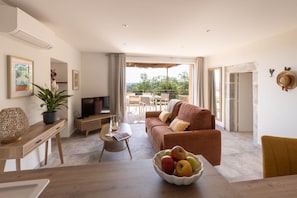 Ein modernes Wohnzimmer mit einer Couch, einem Couchtisch, einem Fernseher und einem Essbereich mit Stühlen.
