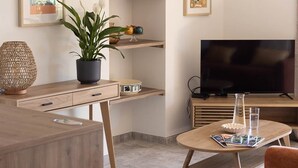 Una sala moderna con comedor, televisor y un frutero sobre la mesa.