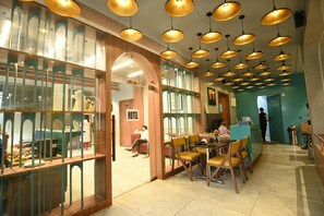 Un hall d’hôtel comprenant un comptoir d’accueil, un espace salon et un espace de réception avec un panneau indicateur.