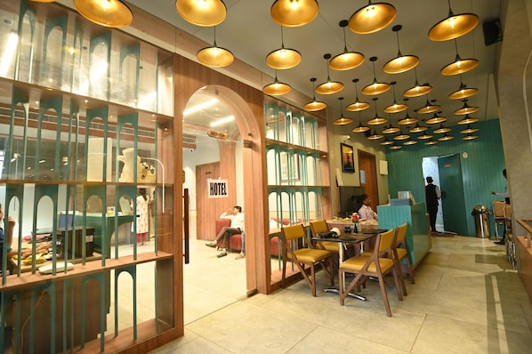 Un hall de hotel con mostrador de recepción, zona de estar y área de recepción con un letrero.