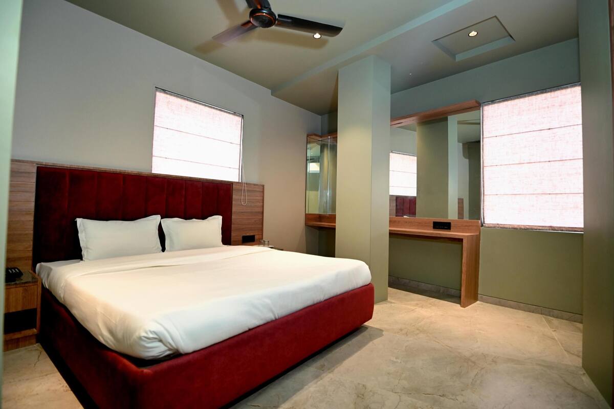 A modern hotel room with a large bed, a desk, and a ceiling fan.