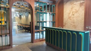Zona de recepción con mostrador de madera, separadores de vidrio y pared de mármol.