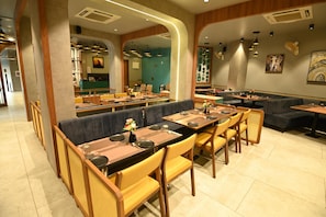 Um restaurante com cabines e mesas, cadeiras de madeira e piso ladrilhado.