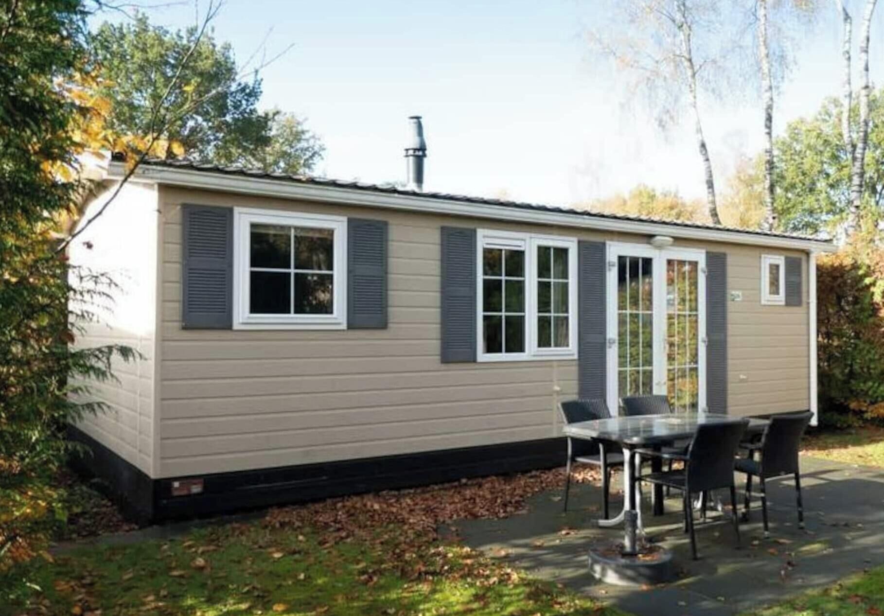 A single-story mobile home with a patio area, a table, and chairs.