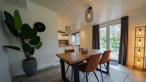 Een moderne keuken met witte kasten, een houten eettafel en een potplant.