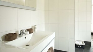 Een badkamer met een witte wastafel, een spiegel en een handdoekrek.