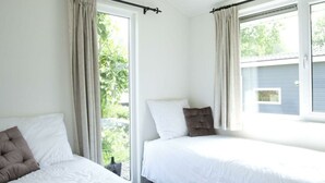 Een kamer met twee bedden, een raam en uitzicht op groen.