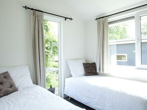 Ein Zimmer mit zwei Betten, einem Fenster und Blick ins Grüne.