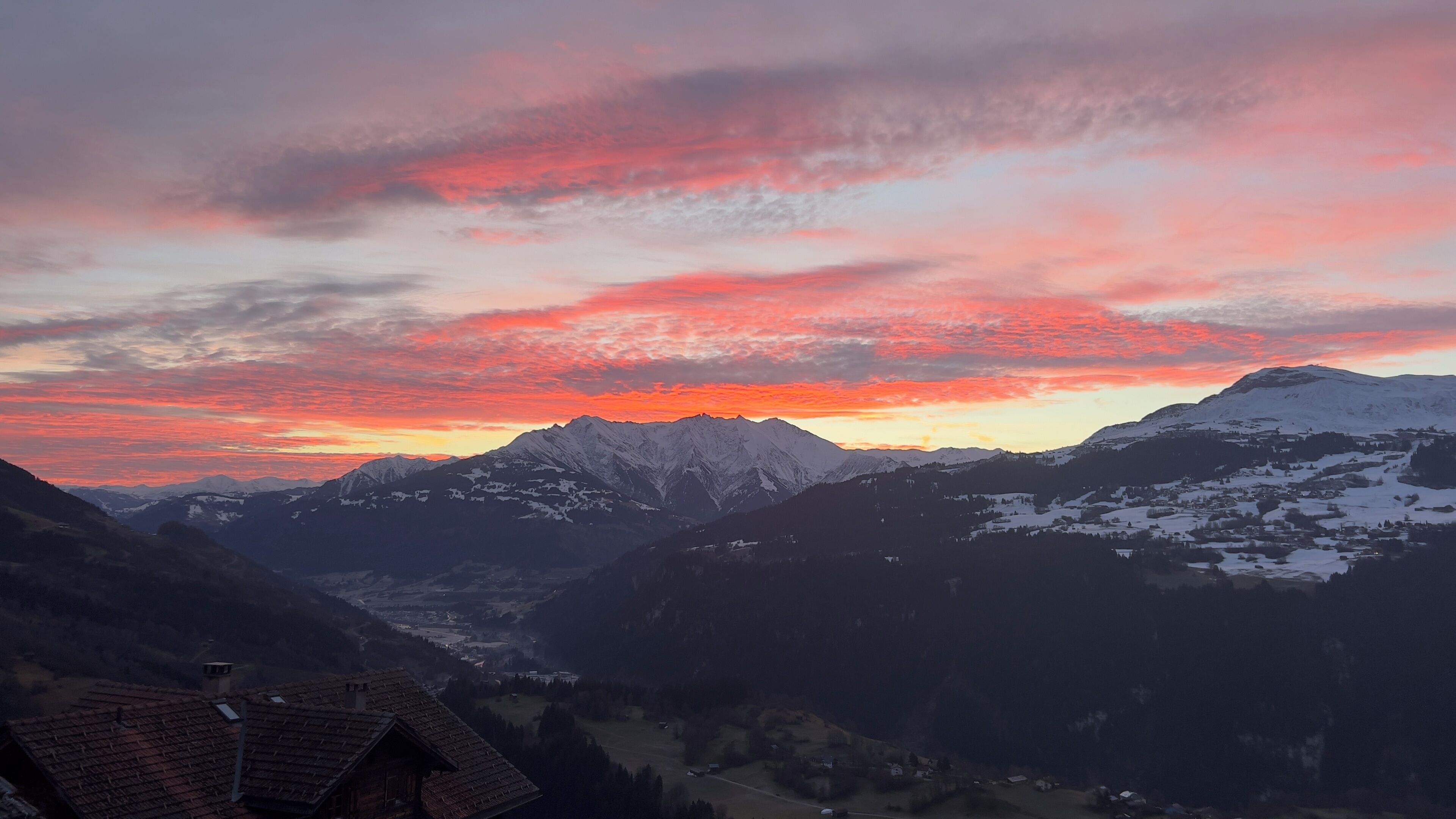 A mountain landscape with snow-capped peaks and a valley below.