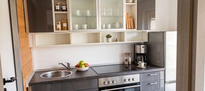 A modern kitchen with a stainless steel sink, a coffee maker, and a bowl of fruit. - Ferienwohnung Seehase (Wilhelmshaven)