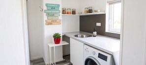 Eine kleine Küche mit Waschmaschine, Spüle und Fenster.