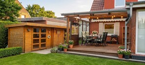 Eine Holzterrasse mit Tisch und Stühlen, umgeben von Topfpflanzen.