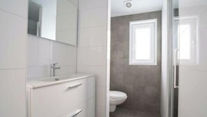 A bathroom with a white vanity, a toilet, and a window. - Hackfort Waterfront 6 (Linden)