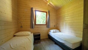 A small cabin room with two beds, a window with curtains, and a wooden ceiling. - Holiday Home in Maarn With Terrace (Maarn)