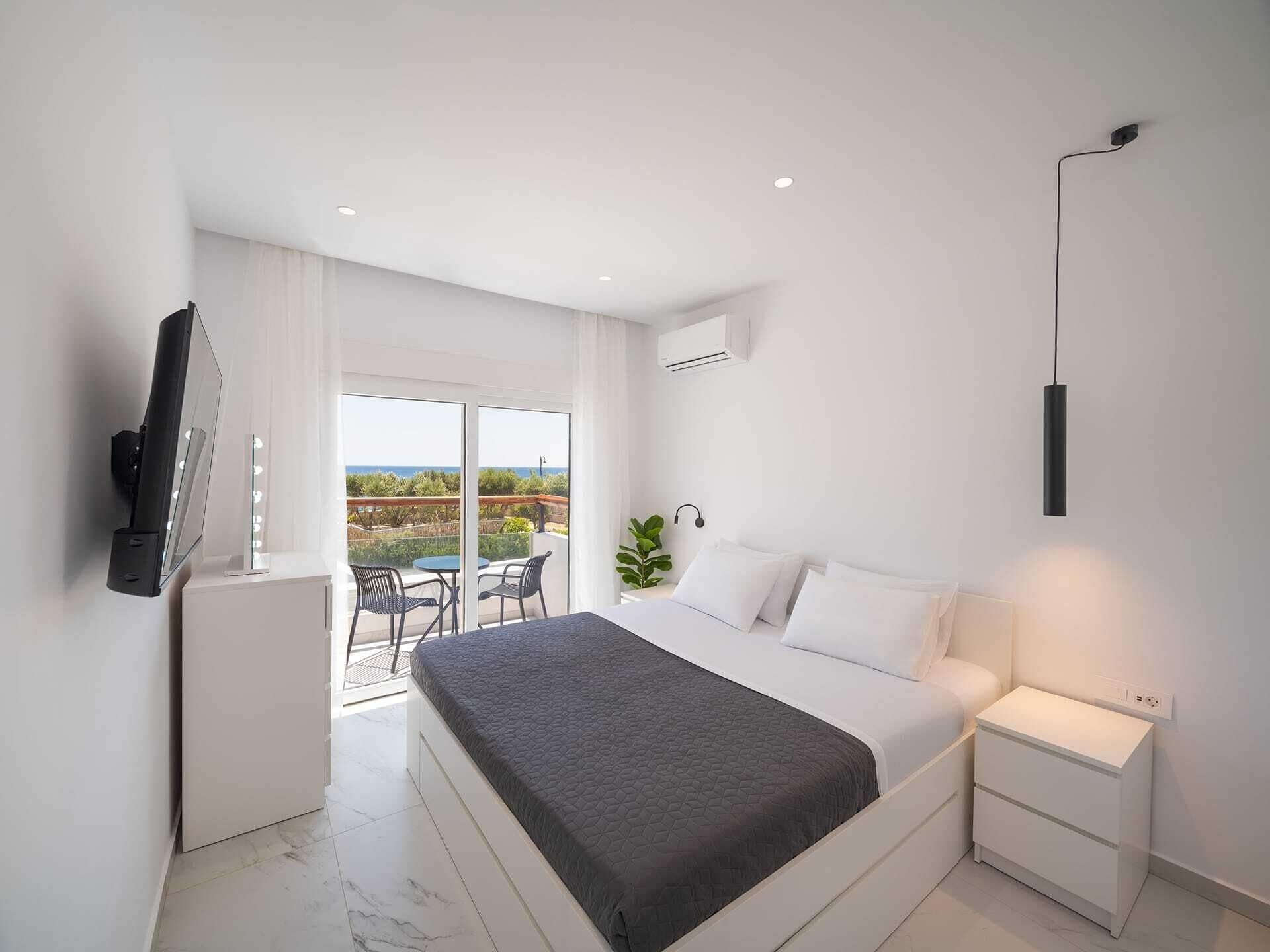 Een moderne slaapkamer met een bed, nachtkastje en een aan de muur bevestigde televisie.