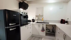 A compact kitchen with a black refrigerator, a stove, and a sink.