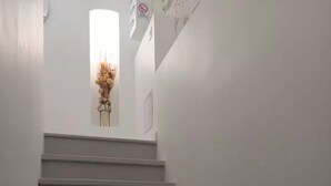 Eine Treppe führt zu einer Empfangshalle mit einer Vase getrockneter Blumen.