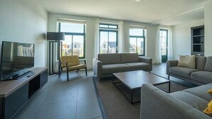 Una sala de estar moderna con sofá, sillón, mesa de centro y televisor.