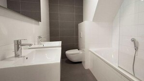 Un baño moderno con una bañera grande, un inodoro independiente y un lavabo.