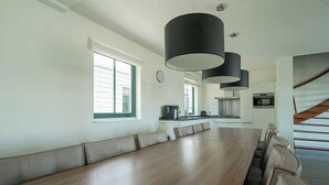 Una cocina moderna con comedor que cuenta con una mesa de madera larga y bancos acolchados.
