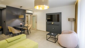 A modern living room with a sofa, a round chair, a coffee table, a TV, and a pendant light.