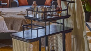 A woman in a room with a sofa, a table with drinks, and a window with curtains. - Minimalist - Lake Pichola Edit (Udaipur)